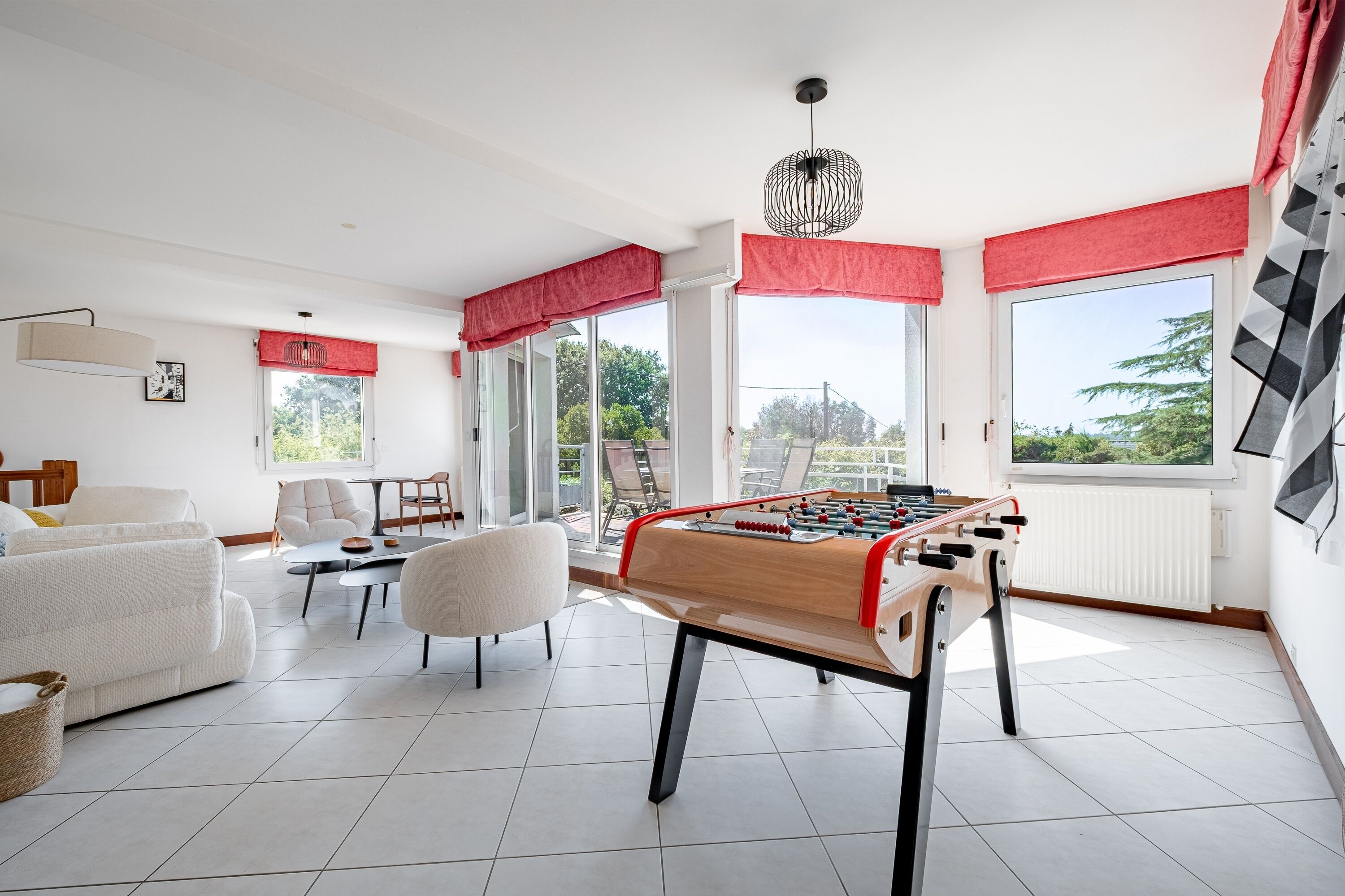 Un salón luminoso con mesa de futbolín, sofá y mesa de comedor.