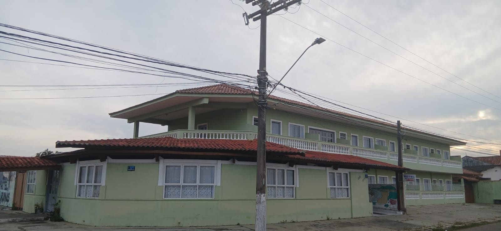 Un edificio de dos pisos con un balcón en el nivel superior, techo plano y varias ventanas.