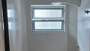 Un baño pequeño con inodoro, lavamanos, ventana y ducha.