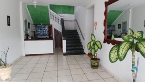 A hallway with a staircase, potted plants, and a mirror. - Suítes Abarebebê Peruíbe (Peruíbe)