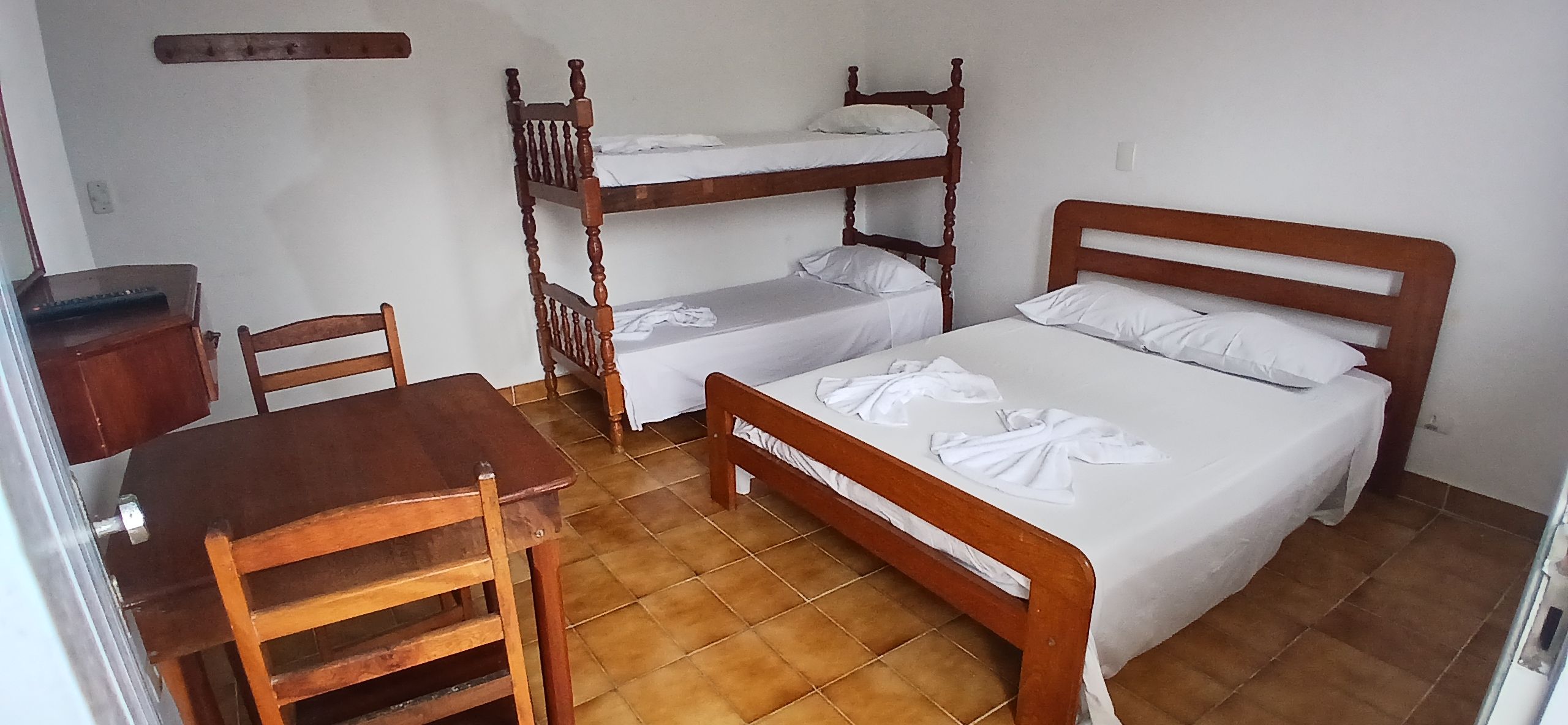Ein Zimmer mit zwei Etagenbetten, einem Holztisch und einem Stuhl.