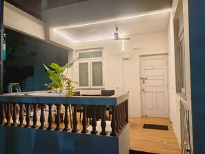 Een balkon met een hekwerk, een plafondventilator en een deur.