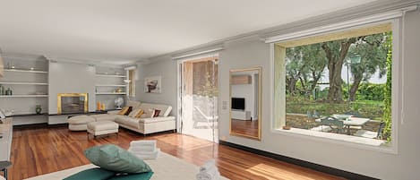 A modern living room with a large window, a sofa, a coffee table, and a TV.