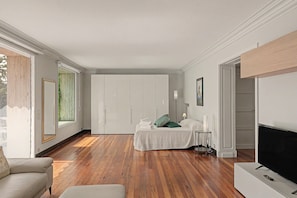 A hotel room with a wooden floor, a bed with white bedding, a TV, and a wardrobe. - LuisHome - Imperia: apartment in villa (Imperia)