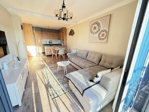 A modern living room with a sofa, a coffee table, and a dining area with chairs.