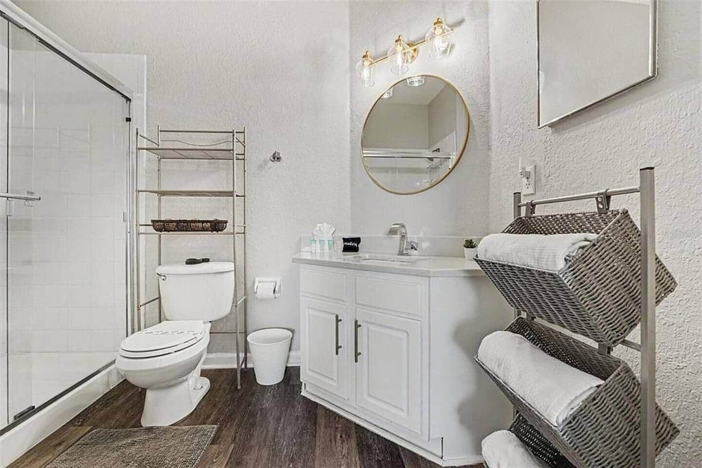 A bathroom with a toilet, a sink, a mirror, and a shower area.