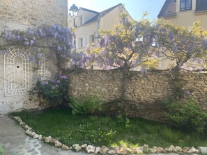 Un mur de pierre avec une fenêtre et un arbre aux fleurs violettes.