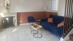 A living room with a blue sofa, a small table, a chair, a fireplace, and a window with blinds.