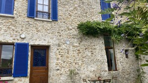 A stone building with blue shutters, a wooden door, and a small window.