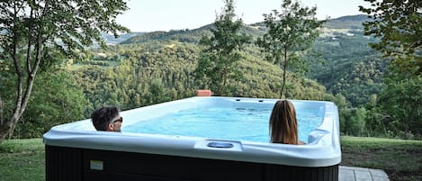 A hot tub with a view of a forested hillside.