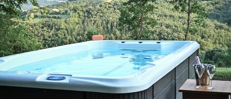 Un jacuzzi en una terraza con vistas a una ladera boscosa.