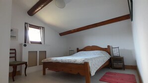 A bedroom with a single bed, a chair, a small table, a window, and a red rug. - Charming, fully equipped apartment in a chalet for a couple, with a panoramic view (sallanches)