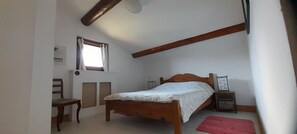 Ein Schlafzimmer mit einem Einzelbett, einem Sessel, einem kleinen Tisch, einem Fenster und einem roten Teppich.