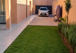 Une voiture est garée dans une allée, avec une pelouse et des plantes de chaque côté.