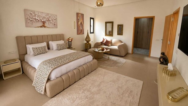 A bedroom with a large bed, a sofa, a coffee table, and a TV.