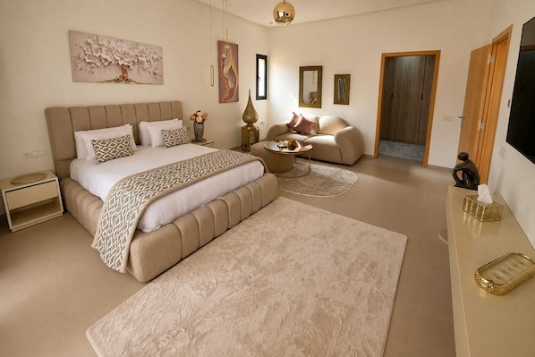 Une chambre à coucher avec un grand lit, un canapé, une table basse et un téléviseur.