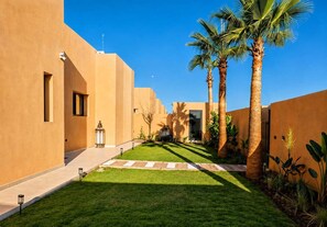 Une cour intérieure agrémentée de palmiers, un sentier et un bâtiment doté d’un toit plat.