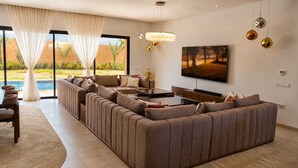 A modern living room with a large sectional sofa, a flat-screen TV, and a dining area.