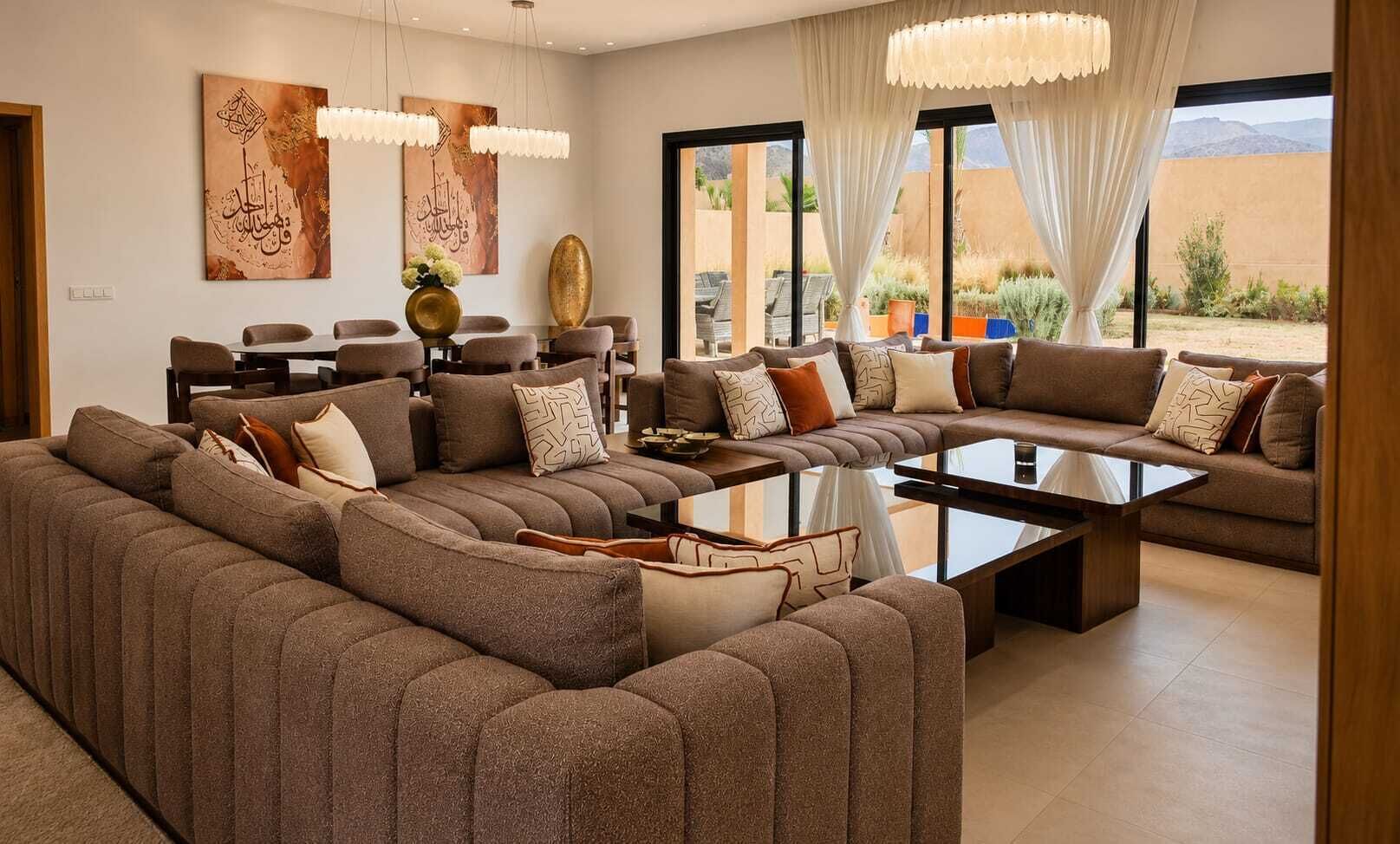 Un salon moderne avec un canapé d’angle, une table basse et un coin repas avec des chaises.