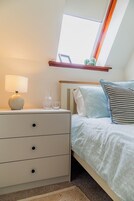 Un dormitorio con cama, una mesita de noche, una lámpara y una ventana con vista a cactus.