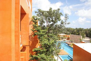 Et resort med swimmingpool, orange bygningsfacader og frodig vegetation.