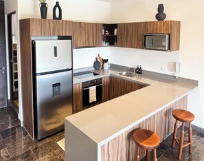A modern kitchen with a stainless steel refrigerator, a microwave, and a built-in oven. - Luxury 3BR Tulum Penthouse with Private Pool (Tulum)