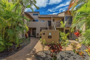 A multi-story building with a central staircase, surrounded by tropical plants and a clear sky. - Wailea Ekahi Village 3A - Townhome Near Keawakapu Beach (WAILEA)