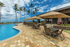 A poolside area with outdoor seating and umbrellas, palm trees, and a view of the ocean. - Wailea Ekahi Village 3A - Townhome Near Keawakapu Beach (WAILEA)