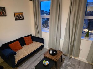 Un salon avec un canapé, une table basse et une vue sur la ville grâce à de grandes fenêtres.