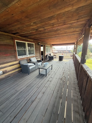 A wooden deck with outdoor furniture, a table, and a view of the surrounding landscape.