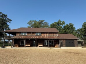 A two-story wooden building with a covered porch, a garage, and a fenced outdoor area.