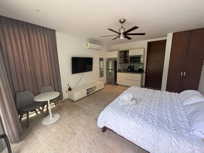Een hotelkamer met een bed, een bureau, een stoel, een televisie, een airconditioning en een kitchenette.
