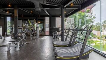 A gym with treadmills, weight machines, and a large window overlooking a green area.