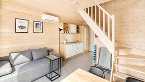 A wooden interior with a sofa, a table, a staircase, and a kitchenette. - Comfortable holiday homes with SPA Rewal (Rewal)
