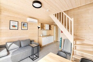 Ein Holzinnenraum mit einer Couch, einem Tisch, einer Treppe und einer Küchenzeile.