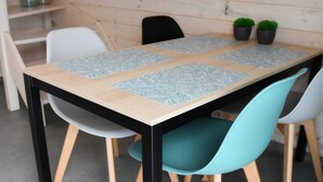 A dining table with four chairs, a wooden wall, and two potted plants. - Comfortable holiday homes with SPA Rewal (Rewal)