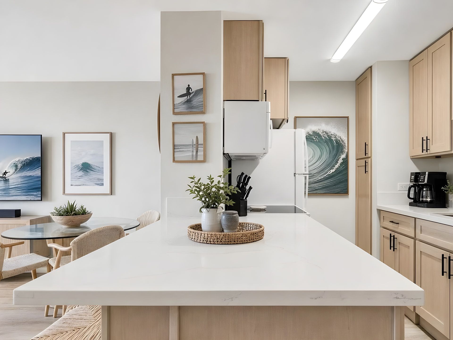 A modern kitchen with a central island, wooden cabinets, and wave-themed artwork.