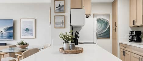 Et moderne køkken med en central ø, træskabe og billedkunst med bølgetema.