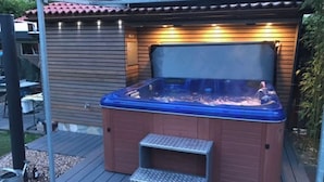 A hot tub with a wooden exterior and a blue interior, placed on a wooden deck with a metal staircase leading up to it. - **** "Barbara Wolfsteiner" Vacation Rental (Steinalben)