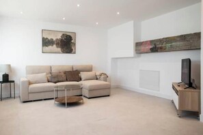 Ein modernes Wohnzimmer mit einem Ecksofa, einem Couchtisch, einem Flachbildfernseher und Kunstwerken an den Wänden.