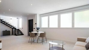 Ein modernes Wohnzimmer mit Treppe, Essbereich und großem Fenster für natürliches Licht.
