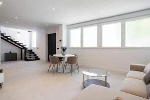 Ein modernes Wohnzimmer mit Treppe, Essbereich und großem Fenster für natürliches Licht.