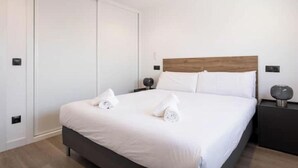 Ein Hotelzimmer mit Bett, Nachttisch, Holz-Kopfteil und Kleiderschrank.