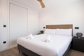 Ein Hotelzimmer mit Bett, Nachttisch, Holz-Kopfteil und Kleiderschrank.