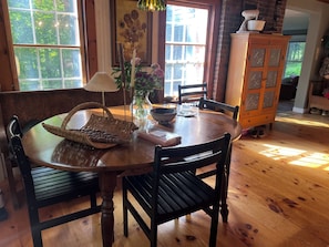 A wooden dining table with chairs, a vase with flowers, a lamp, and a basket.