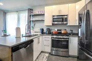 A modern kitchen with stainless steel appliances, including a microwave, oven, and refrigerator. - Private Rooftop w Grill, AC + Free Parking (Seattle)