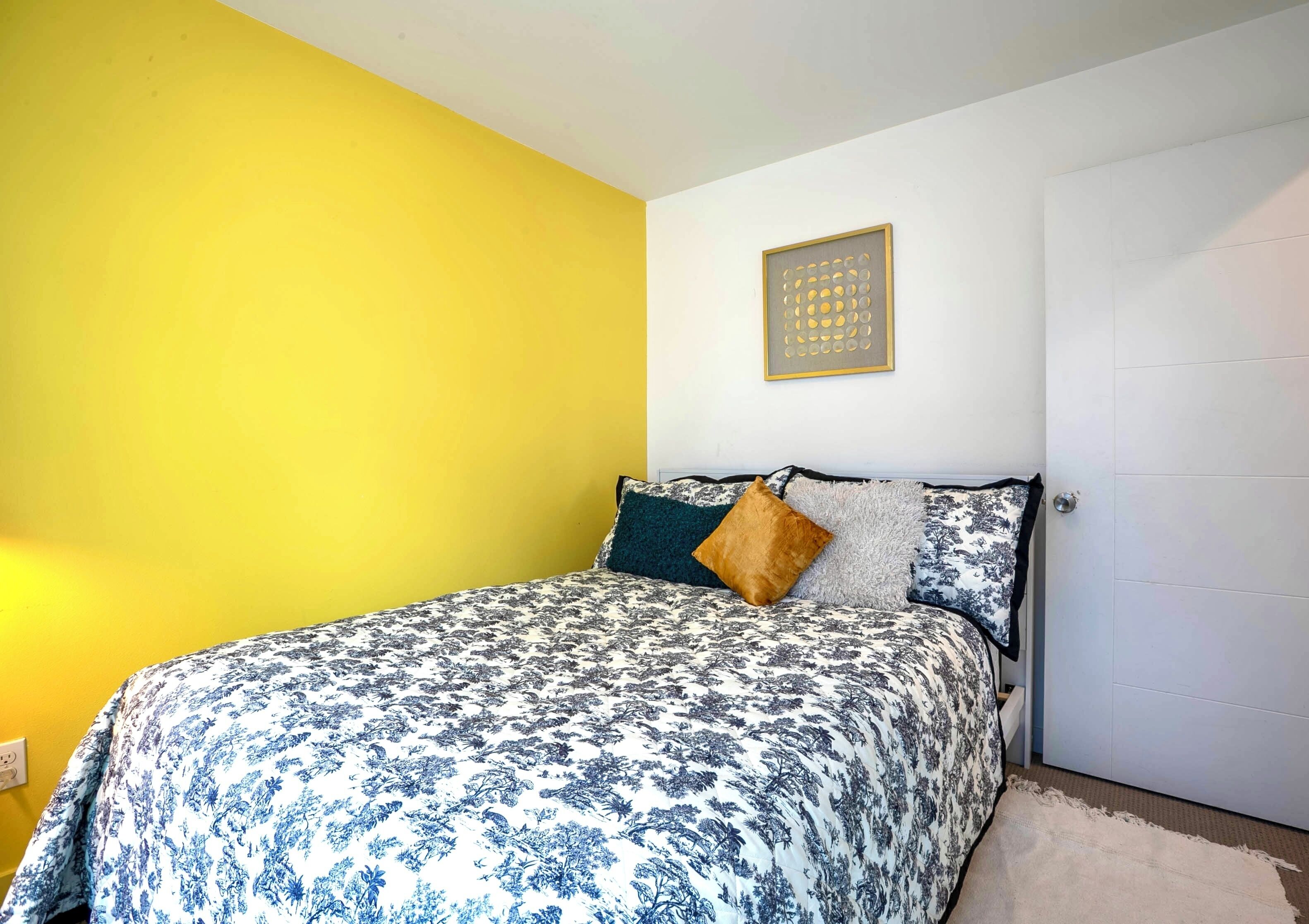 Een slaapkamer met een bed, een kunstwerk aan de muur en een deur.
