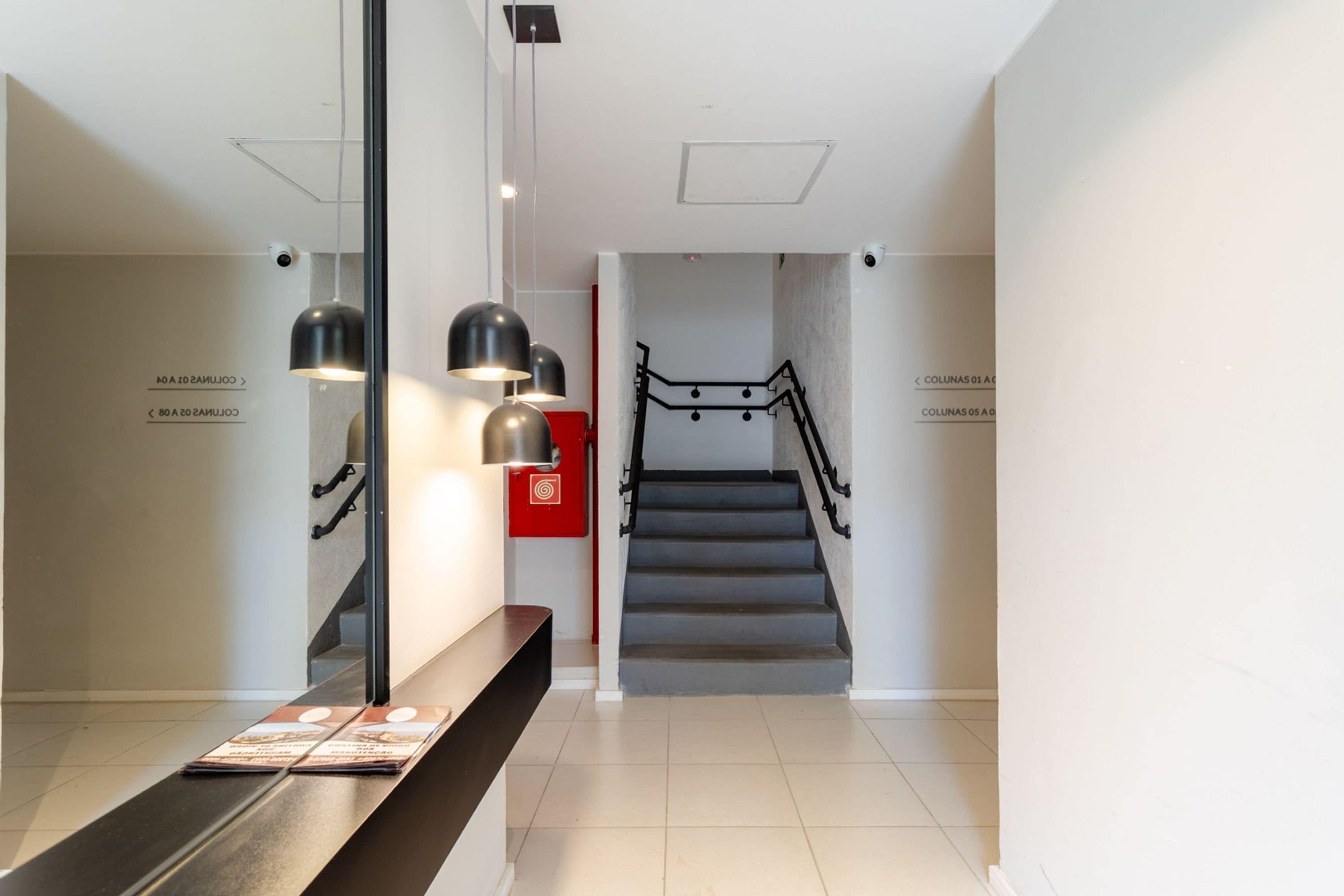 Un intérieur moderne avec un escalier, un banc et des luminaires suspendus.