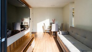 A compact living space with a sofa, a dining table, and chairs. - Apto c Piscina e Varanda Perto do Parque Ol Mpico (Rio de Janeiro)