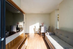 A compact living space with a sofa, a dining table, and chairs. - Apto c Piscina e Varanda Perto do Parque Ol Mpico (Rio de Janeiro)